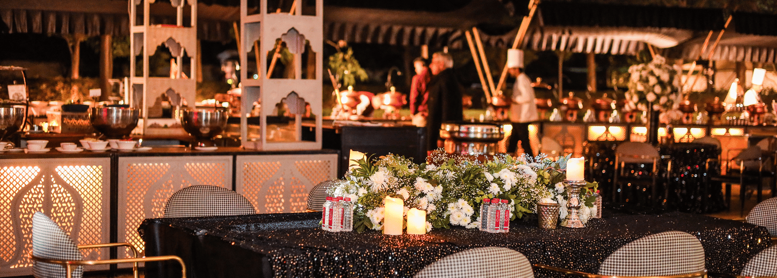 A food counter with serving stations, tables, chairs and floral arrangements at Ananta Spa and Resort, Jaipur