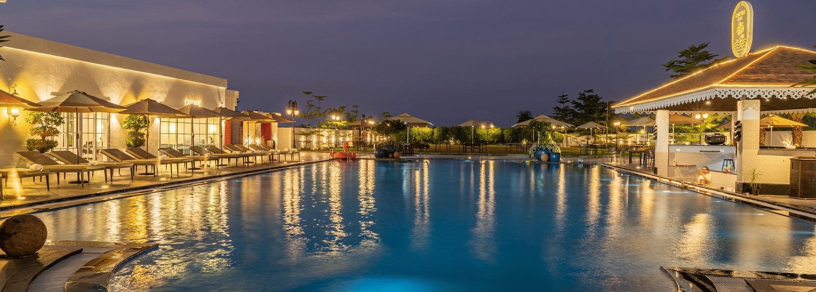 Outdoor swimming pool and surrounding buildings lit gently at dusk or early night, reflecting the sky and lights at Hotel Hukam's Lalit Mahal