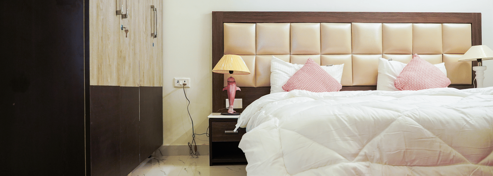 An image of a bedroom featuring a double size bed, a bedside table with lamp, and a wardrobe - Lime Tree 2BHK Service Apartment Near Artemis Gurgaon