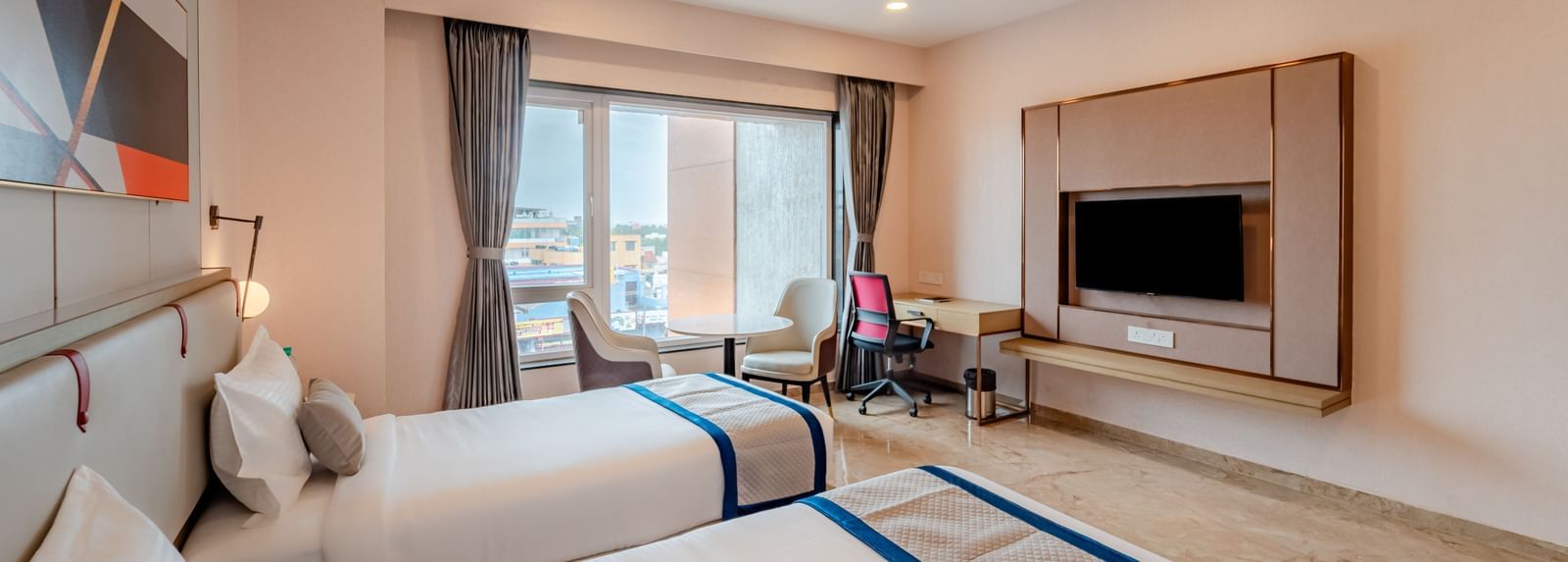 Hotel room with twin beds, a large window, and city view | Superior Room | Pravasa Hotel, Vijayapura