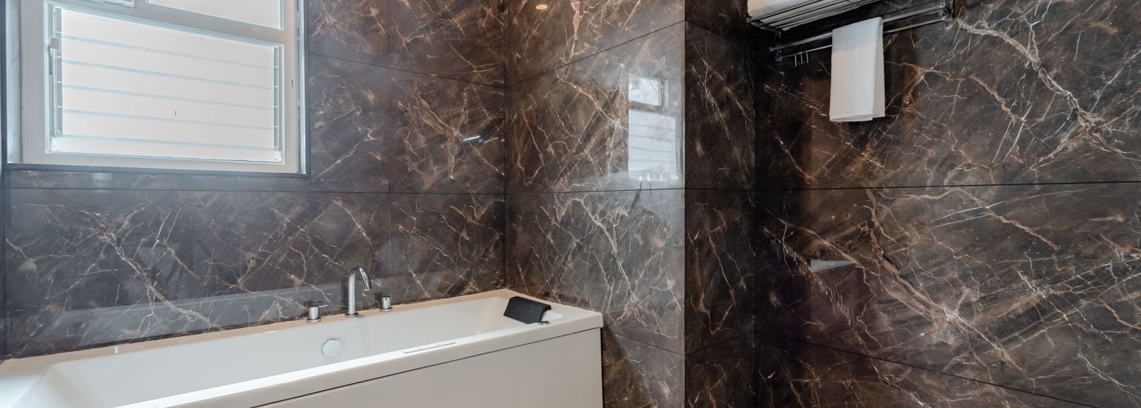 Modern bathroom with a bathtub, shower, and contemporary fixtures | Studio Suite | Pravasa Hotel, Vijayapura