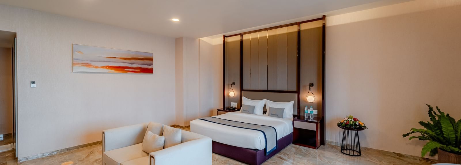 Bright and elegant suite with a bed, living space, and a dining setup | Suite | Pravasa Hotel, Vijayapura