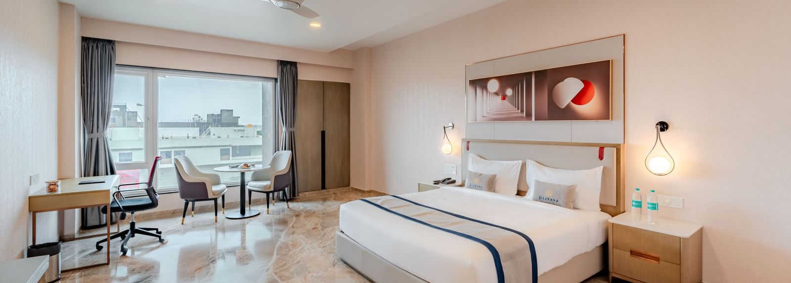 Spacious hotel room featuring a king-size bed, work desk, and city views | Premium Room | Pravasa Hotel, Vijayapura