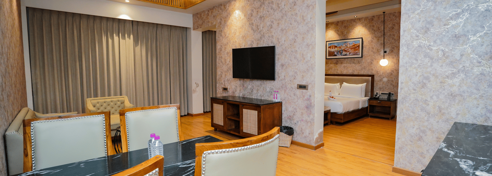 A hotel suite with a dining area and a living area, separated from the bedroom by a partition wall.