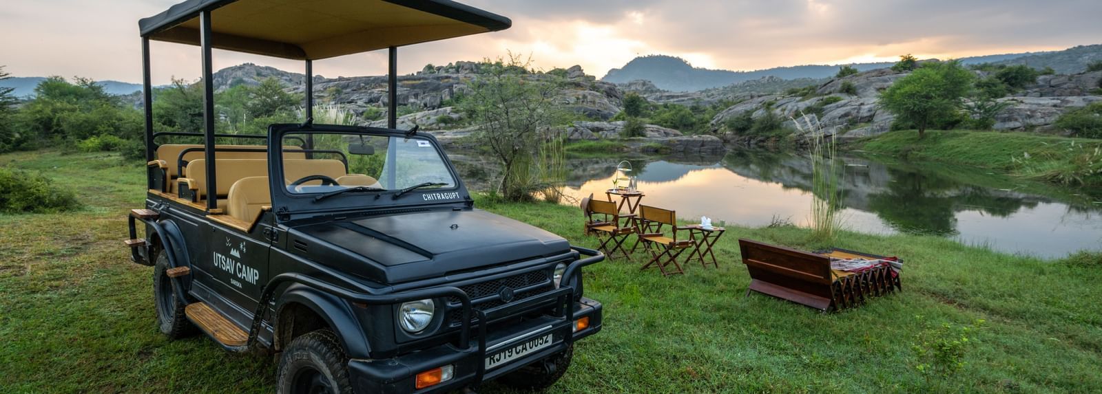 An image of a jeep parked amidst an open field with greenery - Utsav Camp Sariska