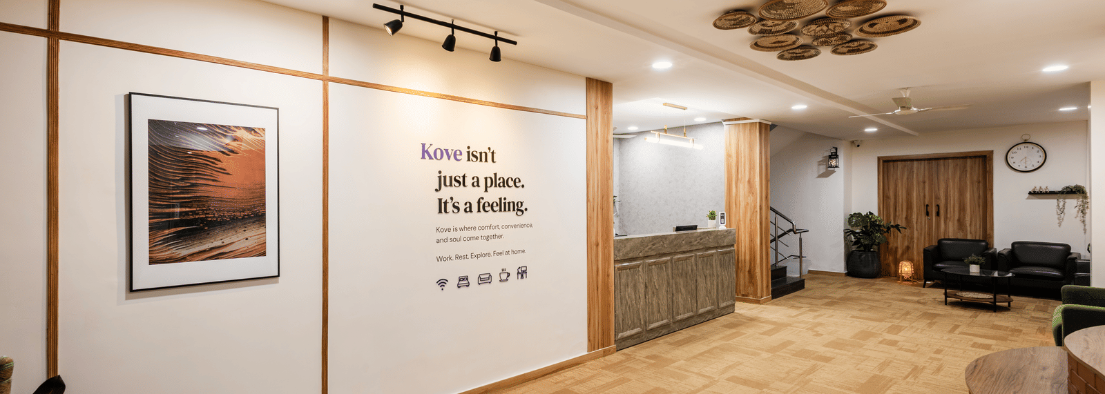 Lobby, entryway, and reception desk of Kove Smart Stays featuring wooden interiors, ample lighting, & signage of a quote on the wall.