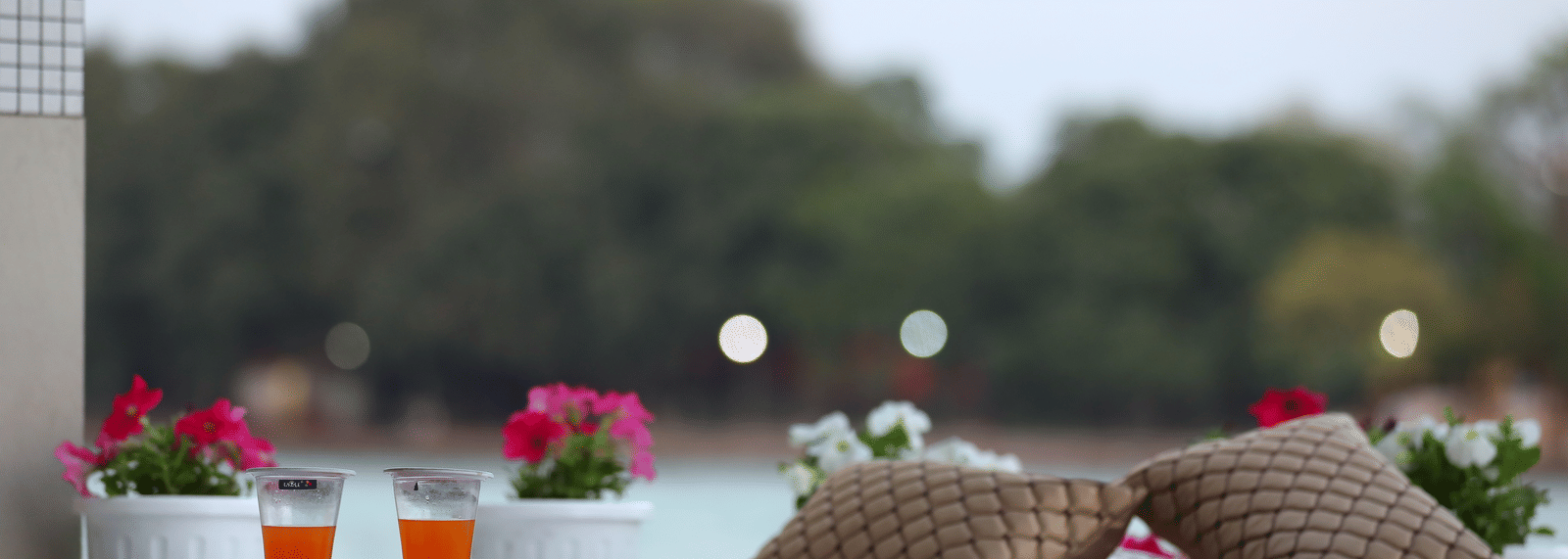 Outdoor seating with pillows and drinks on a table overlooking a body of water - Perfectstayz Premium at Har Ki Pauri Road (Ganga Heights)