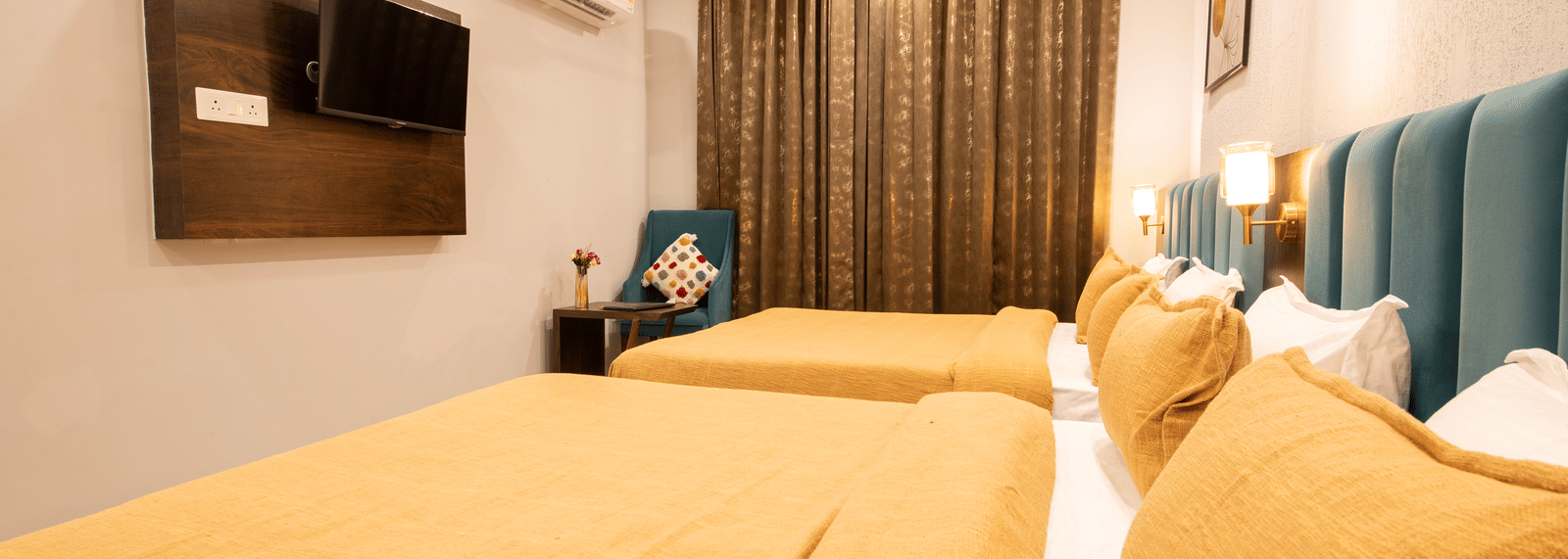 A bedroom featuring 2 king size beds, a wall-mounted television, and a chair at Perfectstayz Premium Laxmi Heritage.