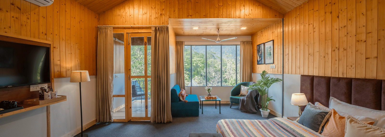 A spacious, wood-paneled room with a vaulted ceiling, a king-size bed, a lounge area, and a large TV.