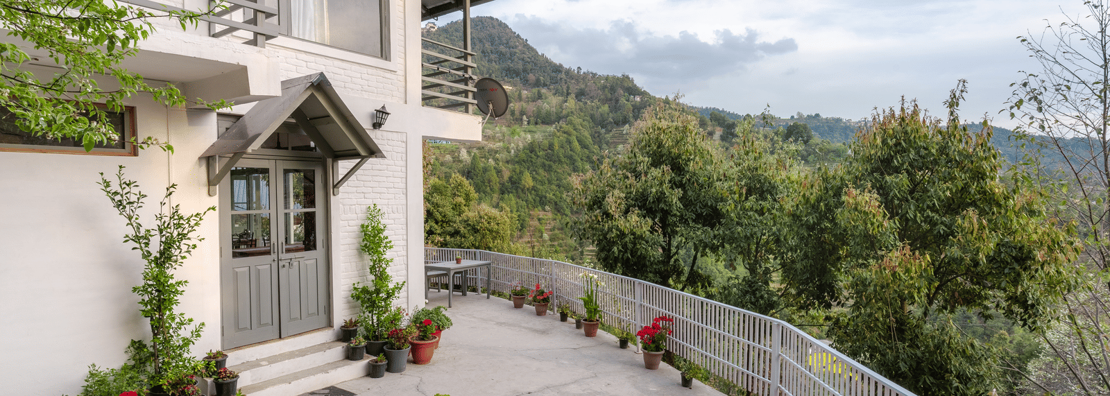 An exterior shot of the Ziran Retreat building, showing the white house with a sloping road in front and a mountain view in the background.