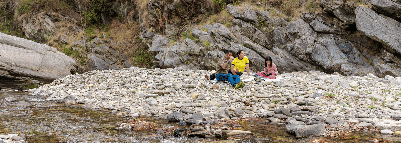 A person sitting on a rock in the middle of a shallow river near Ziran Retreat.