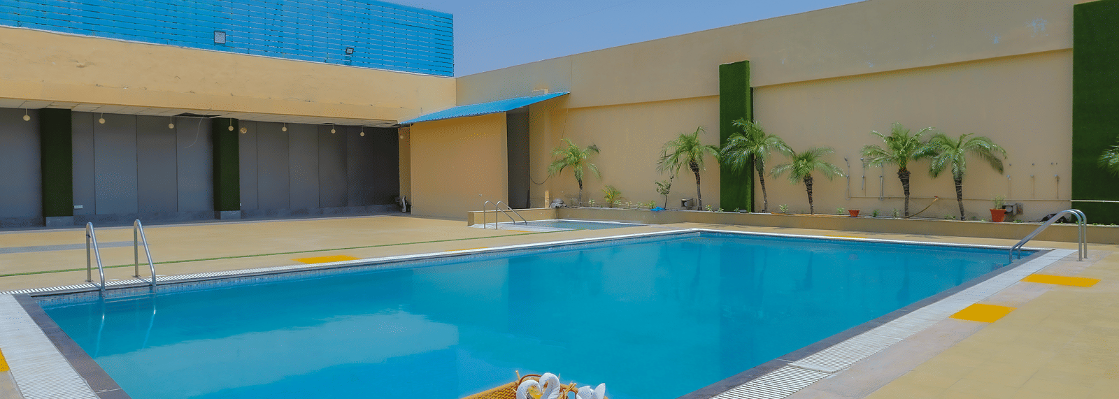 The inviting outdoor swimming pool featuring a white inflatable raft, surrounded by paved areas at The Conway, Meerut.