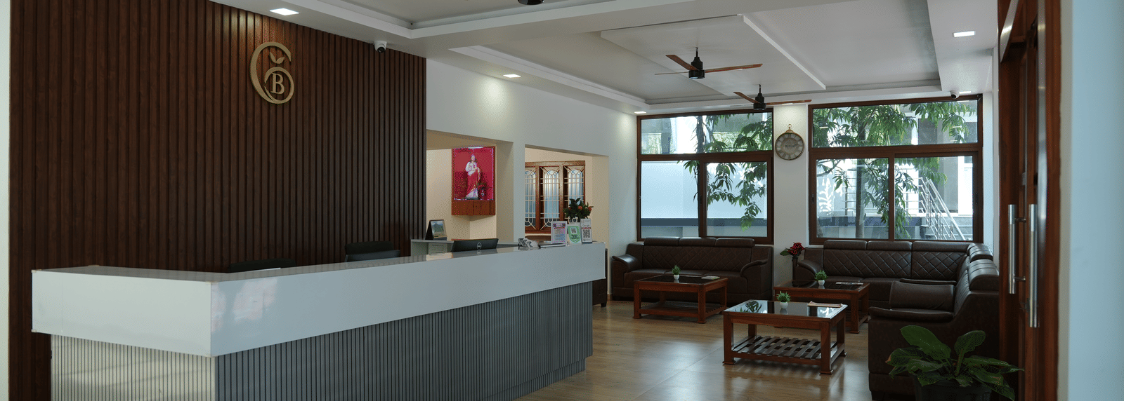 The main reception area of a hotel, featuring a grey and white front desk and a waiting area visible in the background at Coorg Orange Blossom Resort and Spa.