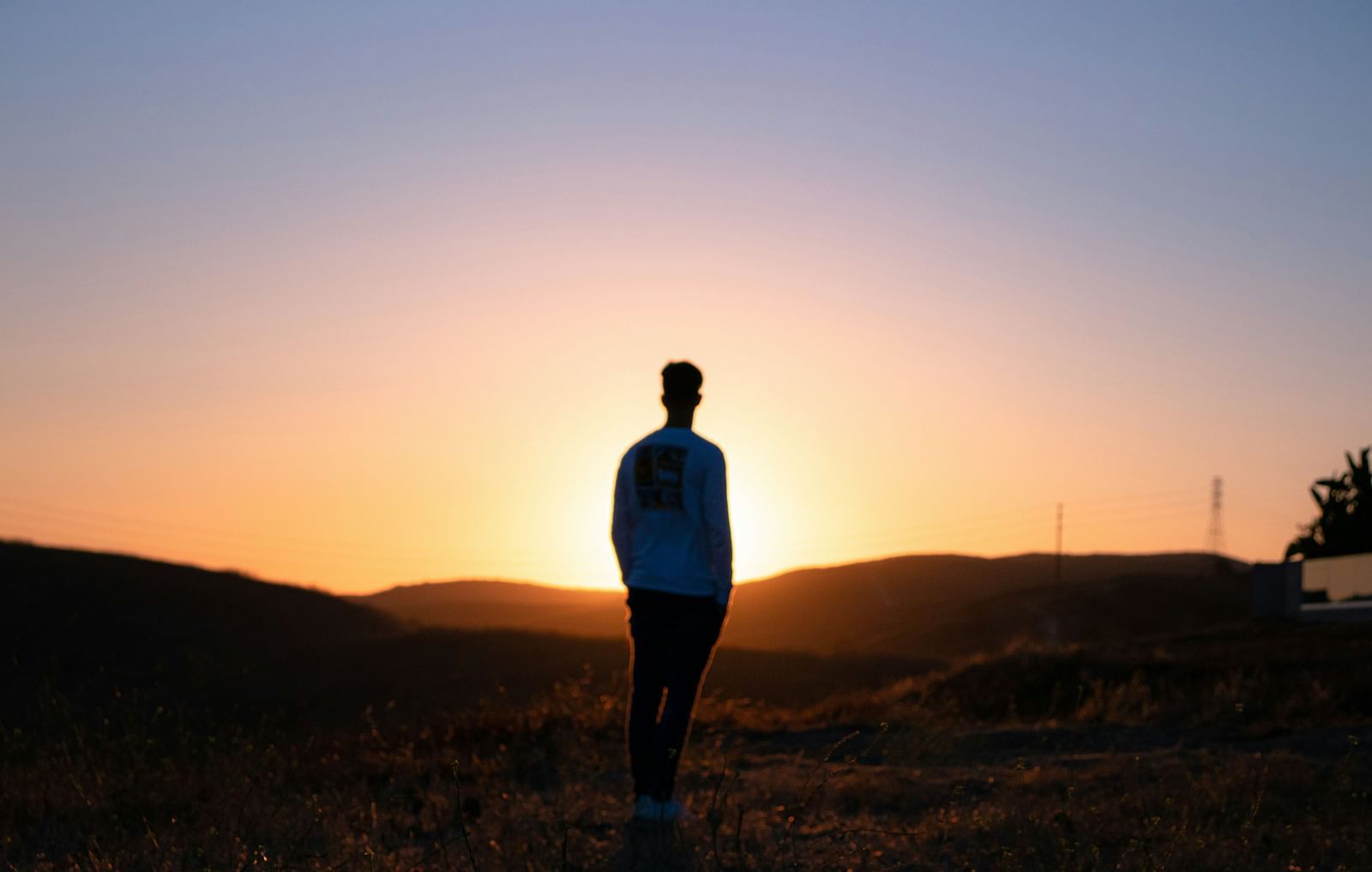 A silhouette of a person standing against a sunset. 