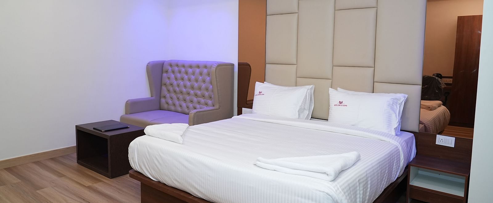 corner view image of the suite with a comfortable double bed along with a cushioned couch at the far end of the room - Hotel Grand Sigma