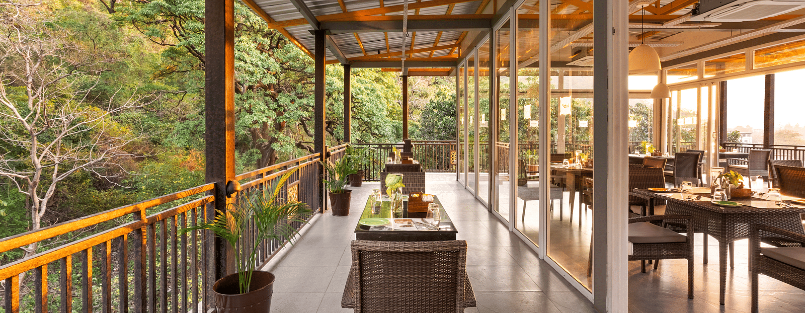 Balcony dining scene overlooking lush forest, with table set and chairs at Bedzzz, Rishikesh