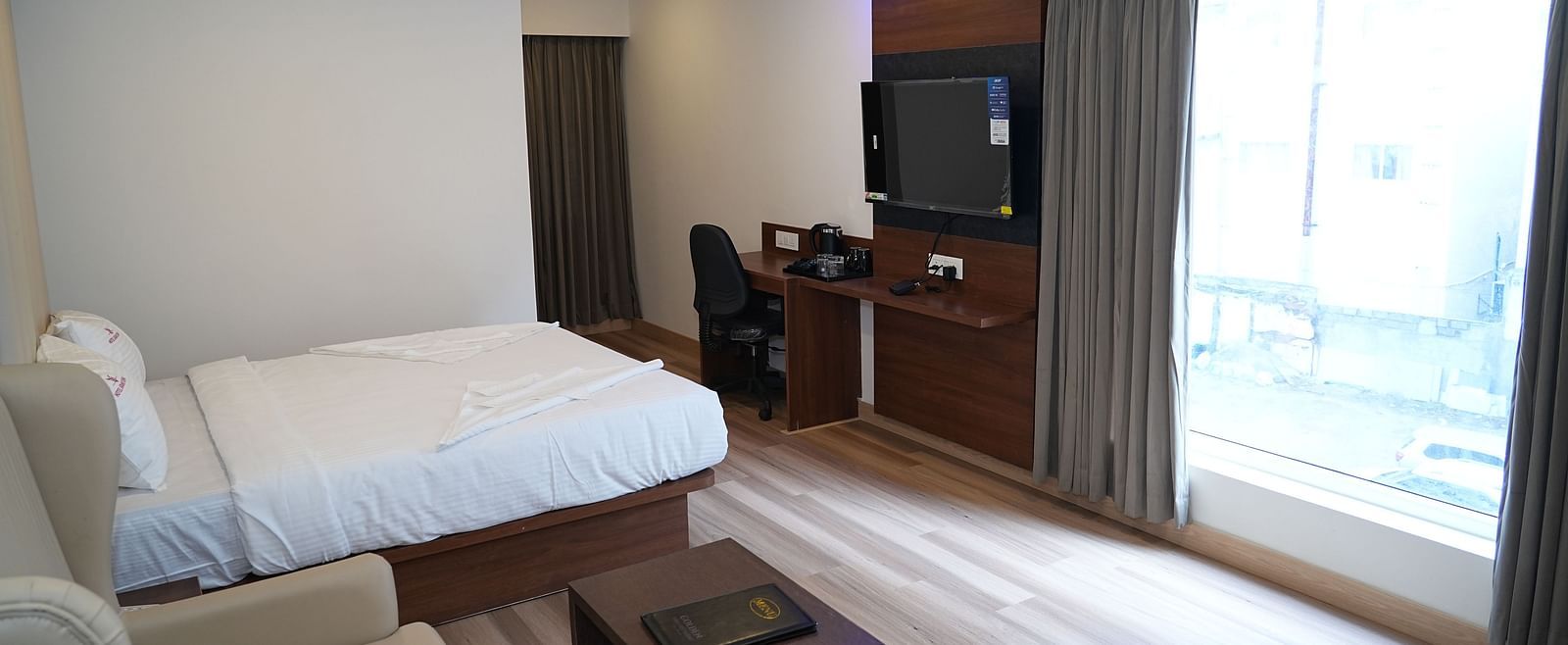 a spacious room featuring a cosy double bed placed right opposite to the huge window allowing ample natural light into the room - Hotel Grand Sigma