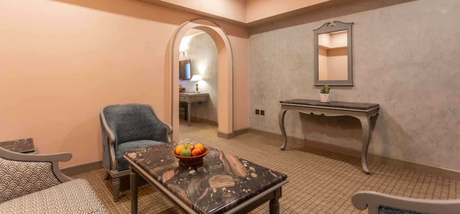  A lounge area at Shilton International, Kochi, with comfortable seating and an arched doorway leading to another room.