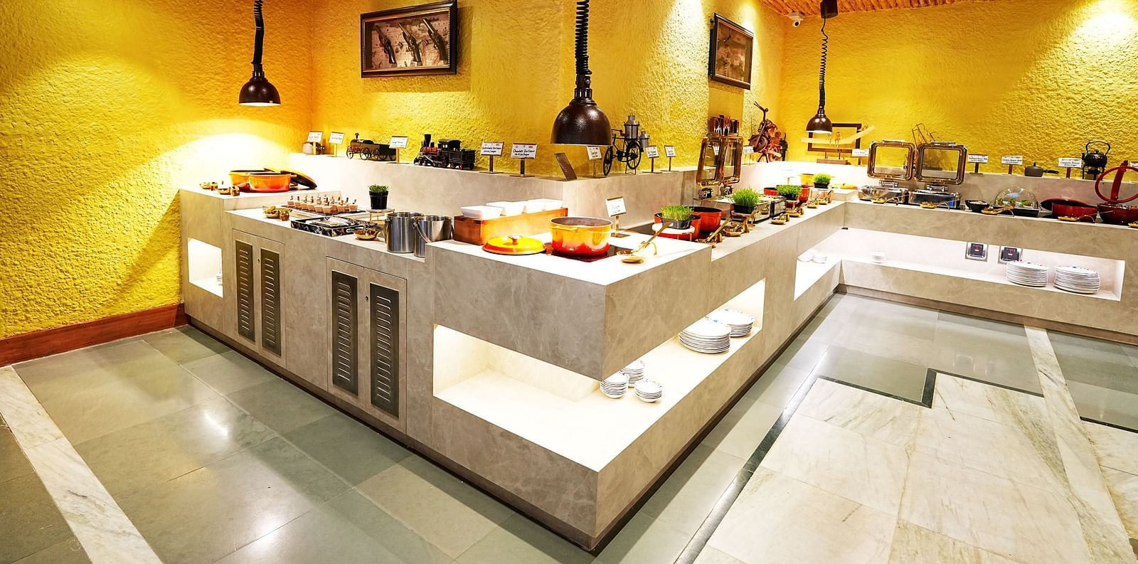 A well-arranged buffet line in a room with yellow walls and wooden ceiling at Tara, Comfort Hotel in Hyderabad - Ramoji Film City.