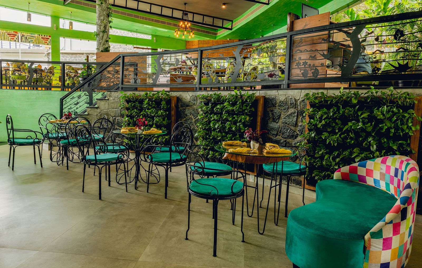 An image of a restaurant with two different areas for dining which are well decorated with plants and other items - An image of a restaurant with different seating arrangement and decorative items - Great Trails Yercaud by GRT Hotels