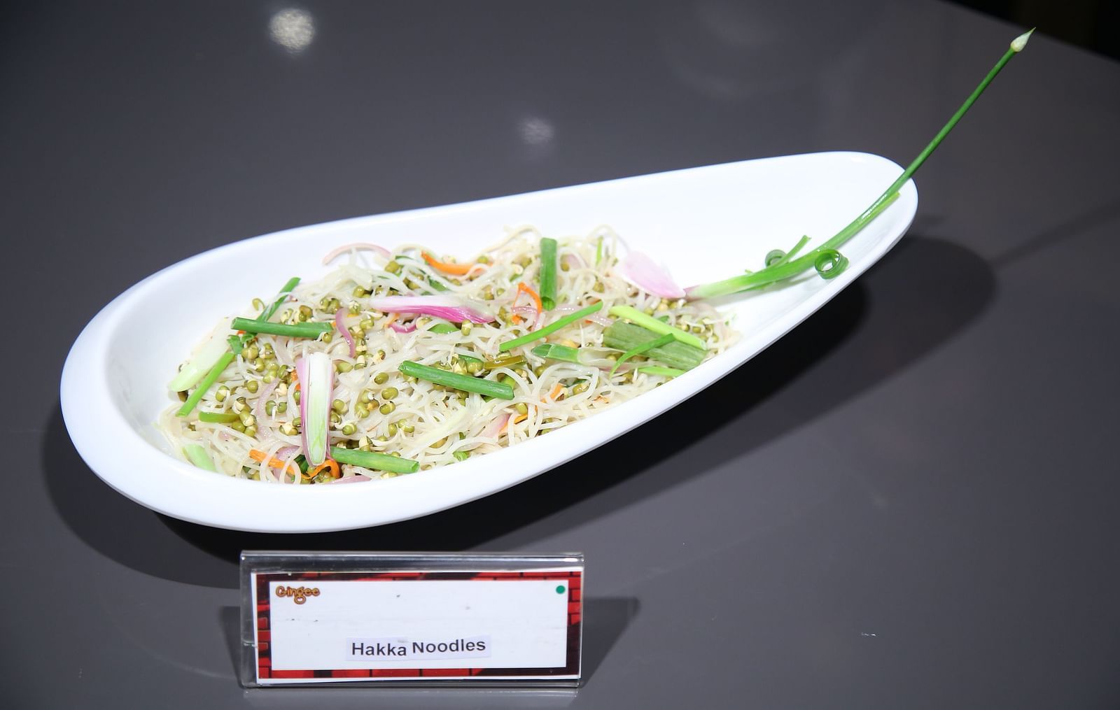 A white oval plate filled with a colorful vegetable chow mein dish.