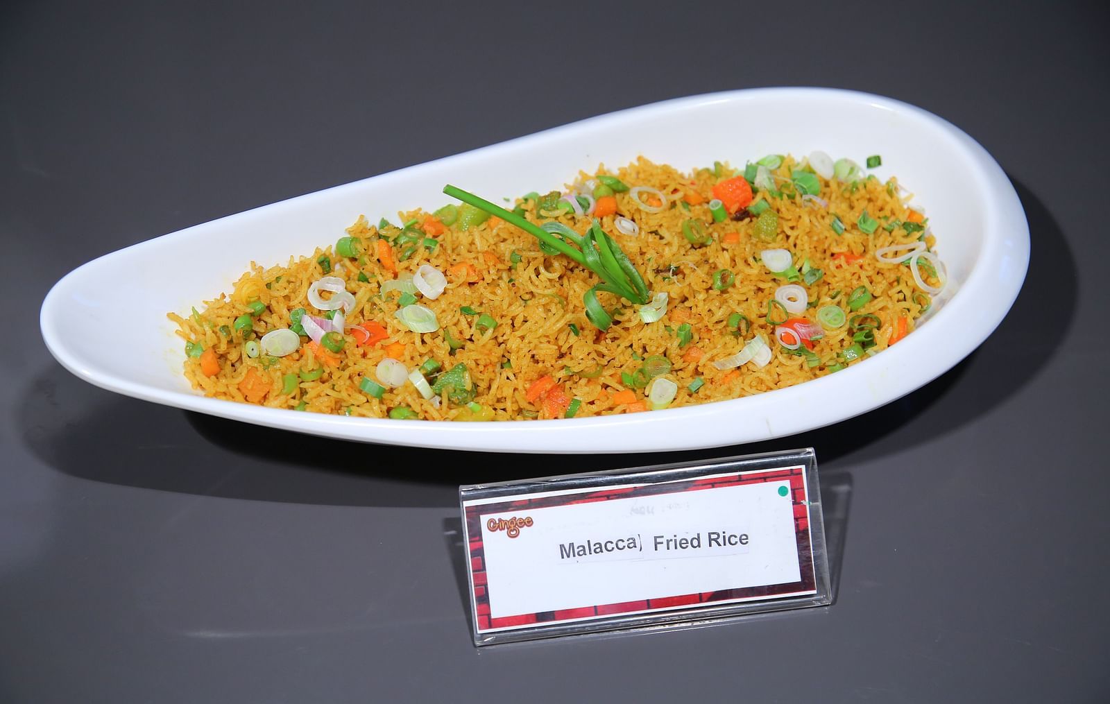 A white oval plate filled with a colorful vegetable fried rice dish.