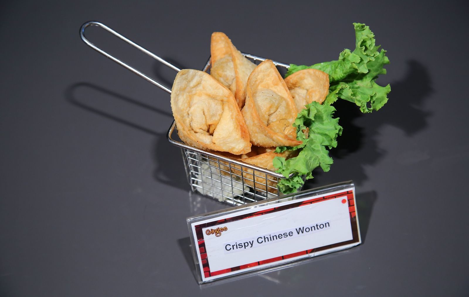 A metal basket filled with crispy samosas, garnished with lettuce.