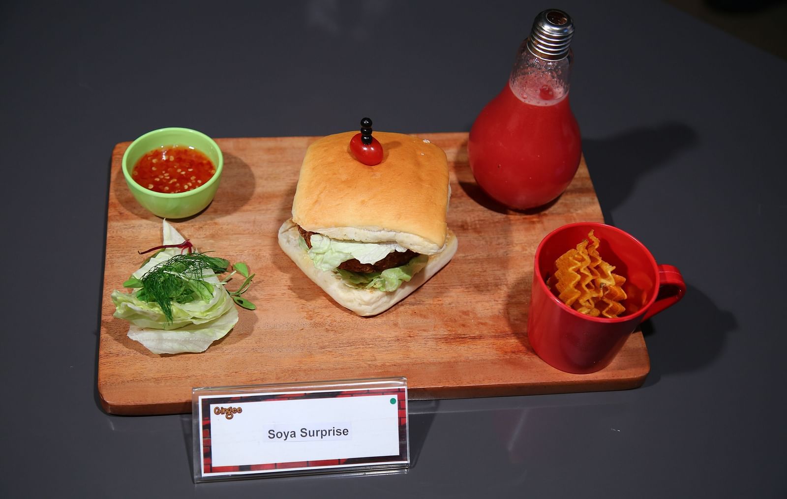 A burger, fries, and a drink served on a wooden board.