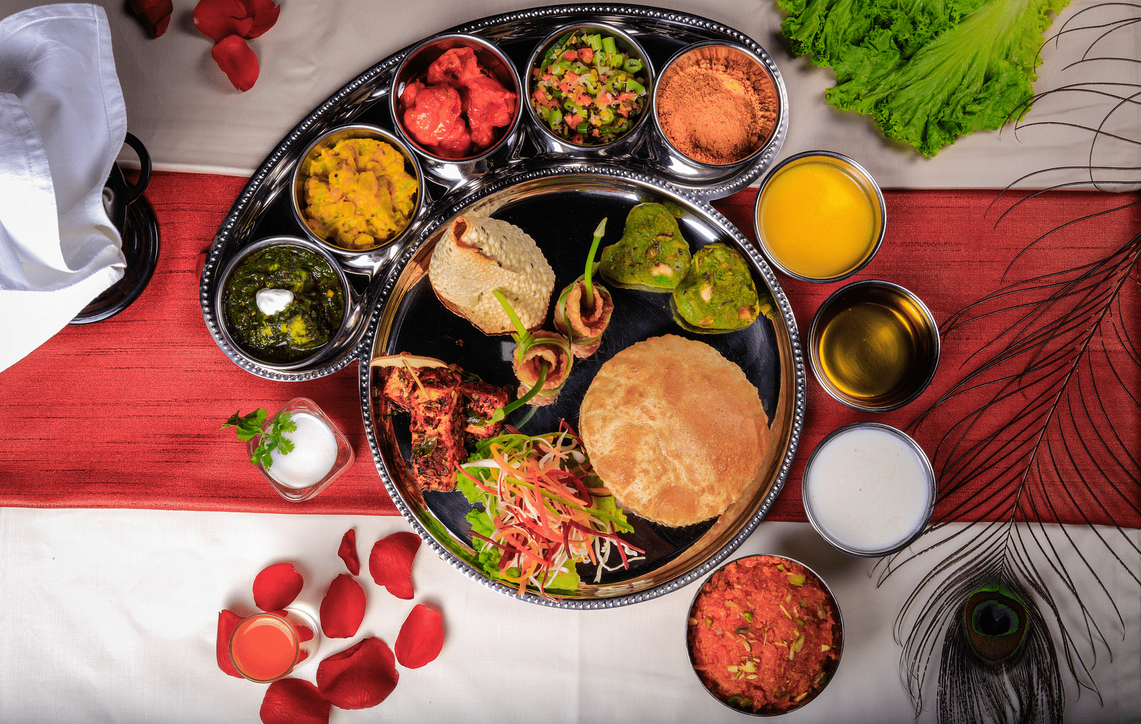 A thali meal with various dishes, including rice, curry, vegetables, and bread.