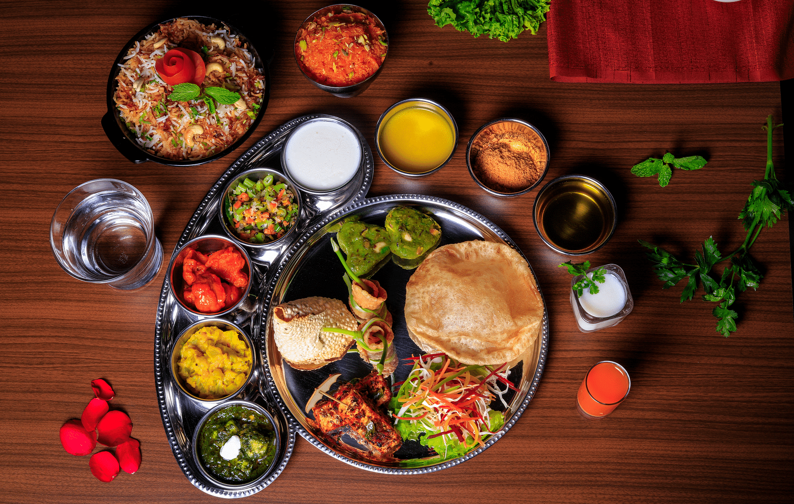 A thali meal with various dishes, including rice, curry, vegetables, and bread.