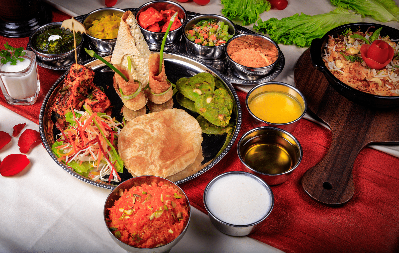 A thali meal with various dishes, including rice, curry, vegetables, and bread.