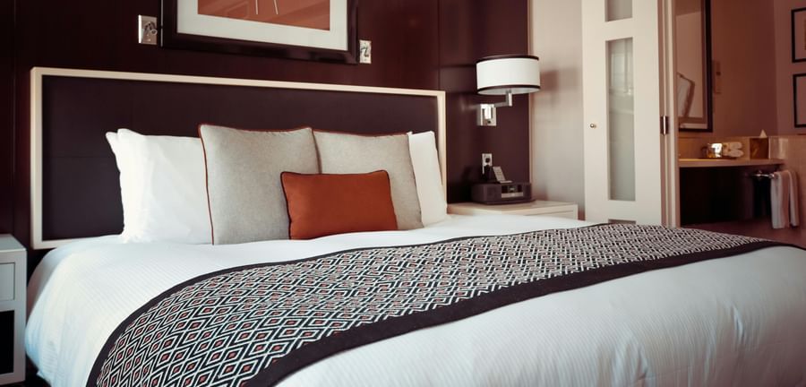 A hotel room with a double bed, soft pillows and an artistic frame.