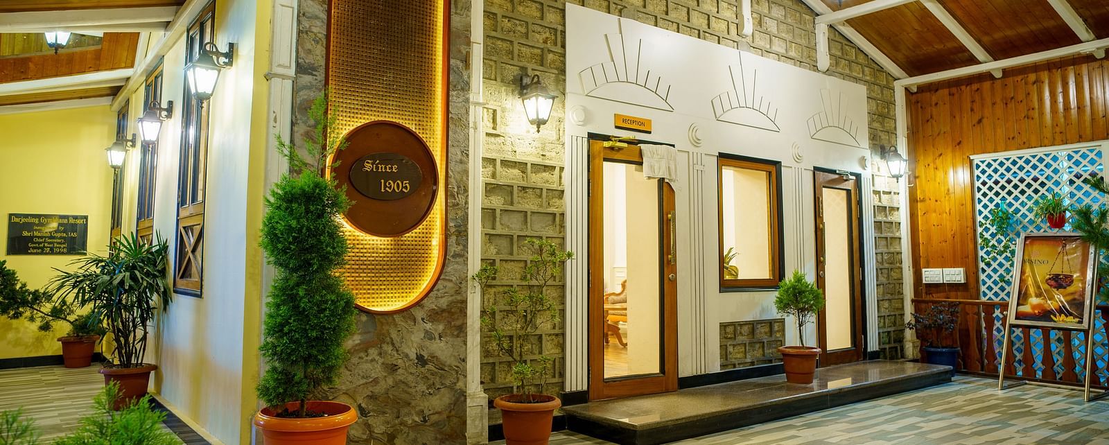 A well-lit interior space of Orsino Spa Resort with wooden ceilings and walls, featuring decorative wall art and potted plants.