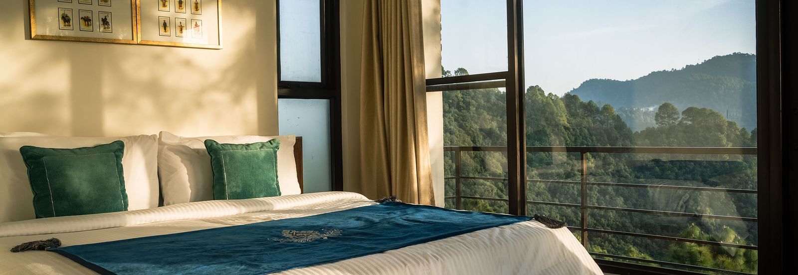 A bedroom with a balcony offering a mountain view and sunlight streaming in at BluSalzz Escapade Resort, Lansdowne