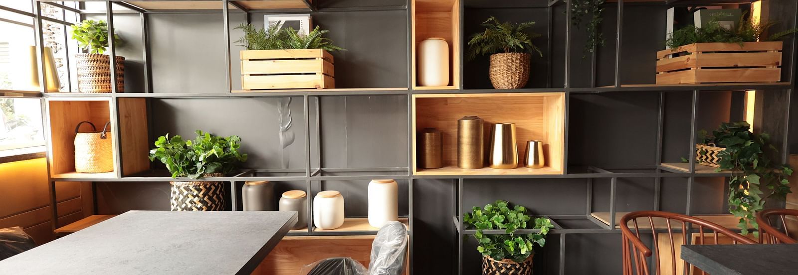 A spacious dining area with a background shelf decorated with plants, pots, and vessels | Cenneys Gateway