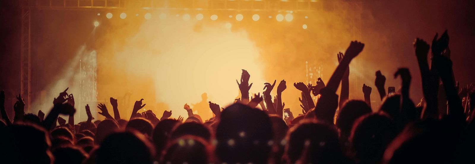 A crowd dancing under colourful lights.
