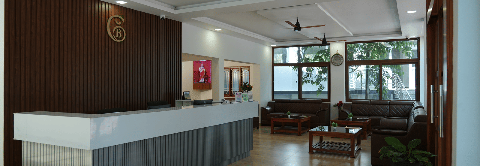 The main reception area of a hotel, featuring a grey and white front desk and a waiting area visible in the background at Coorg Orange Blossom Resort and Spa.