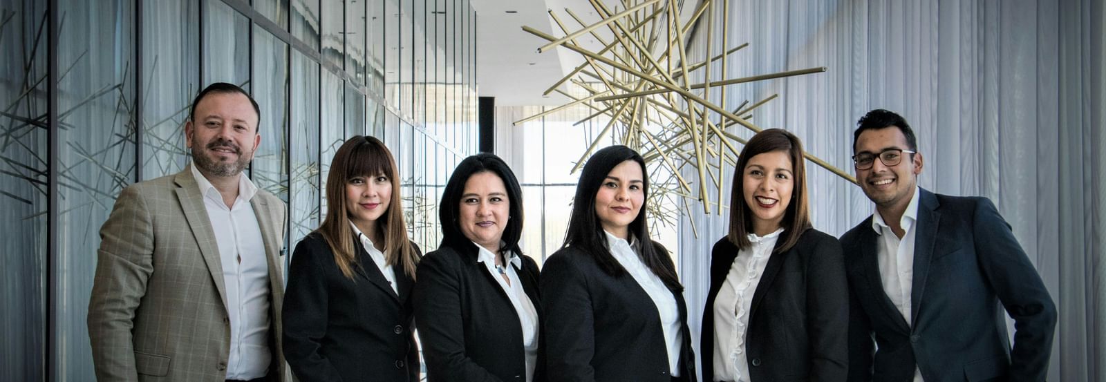 A diverse business team in formal attire posing in a modern office setting. 