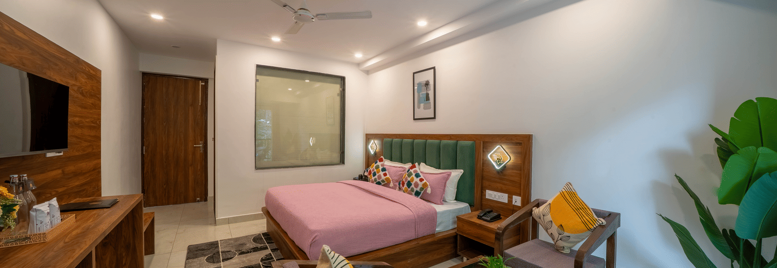 A room with a bed, a sofa with cushions, a coffee table, a wooden desk, and a wall-mounted television in Perfectstayz Premium Mystic Falls, Rishikesh.