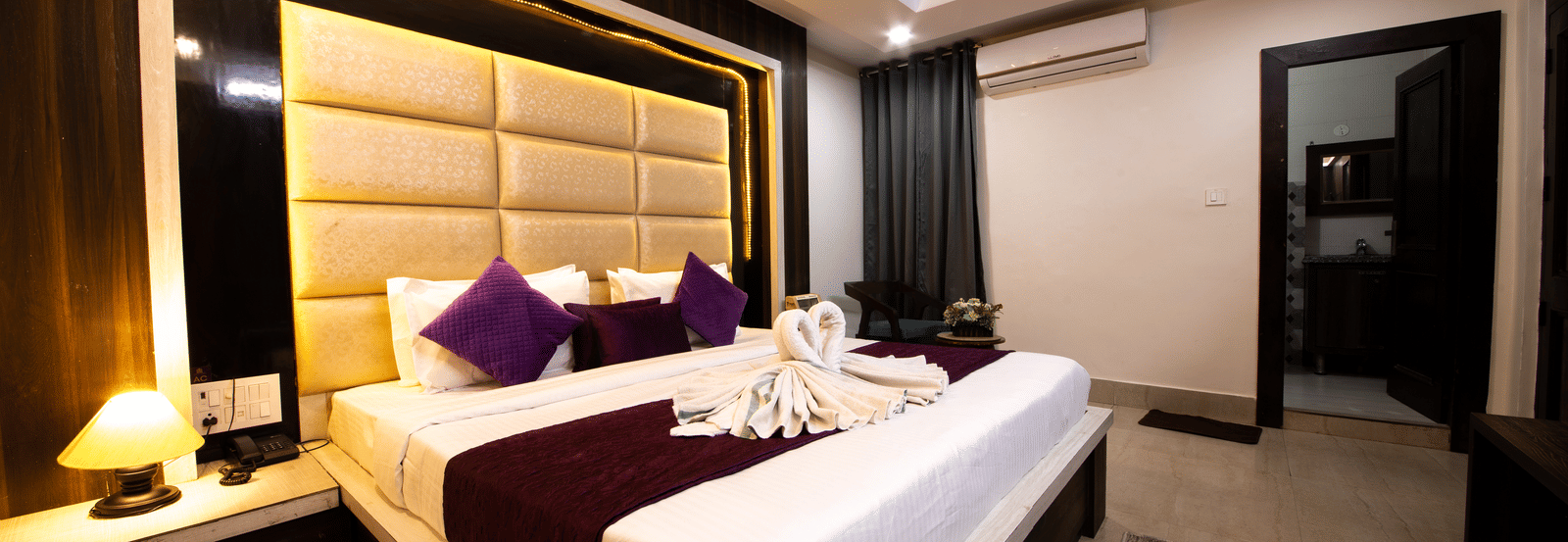 Well-lit hotel room with a large bed, dark wood panelling on the headboard wall, and modern ceiling fan - Perfectstayz Value Grey Castle, Haridwar