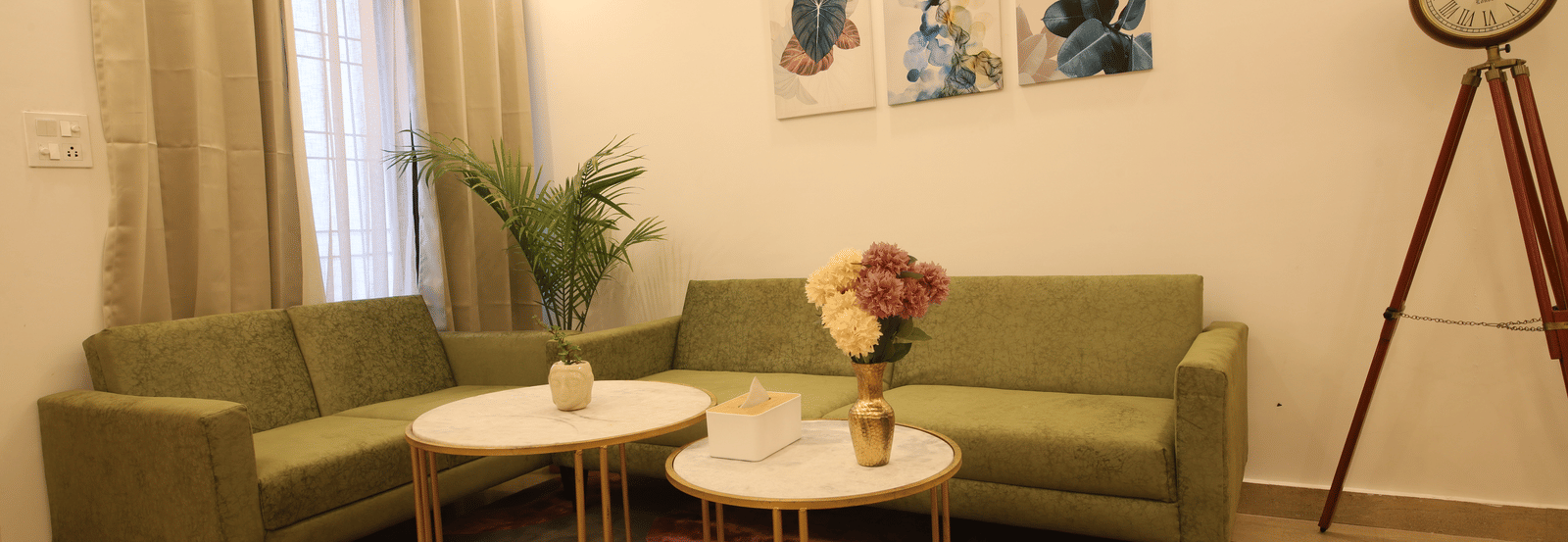 A living room, featuring an olive green sofa, 2 round white coffee tables on a purple rug, and a large tripod floor lamp | Perfectstayz Value Homes, Mussoorie