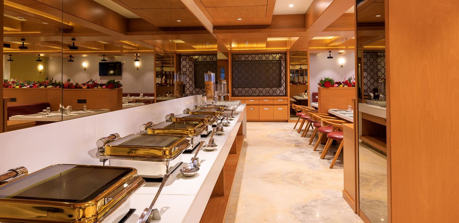 A brightly lit buffet area at Lords Eco Inn Apple Gate features multiple chafing dishes, ready to serve meals.