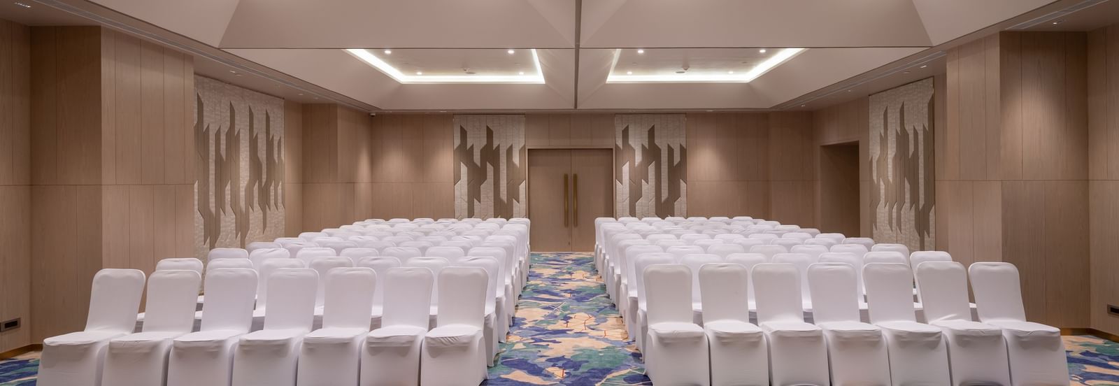 Theatre-style seating in a modern conference hall with patterned carpet at Merlis Hotel, Coimbatore.