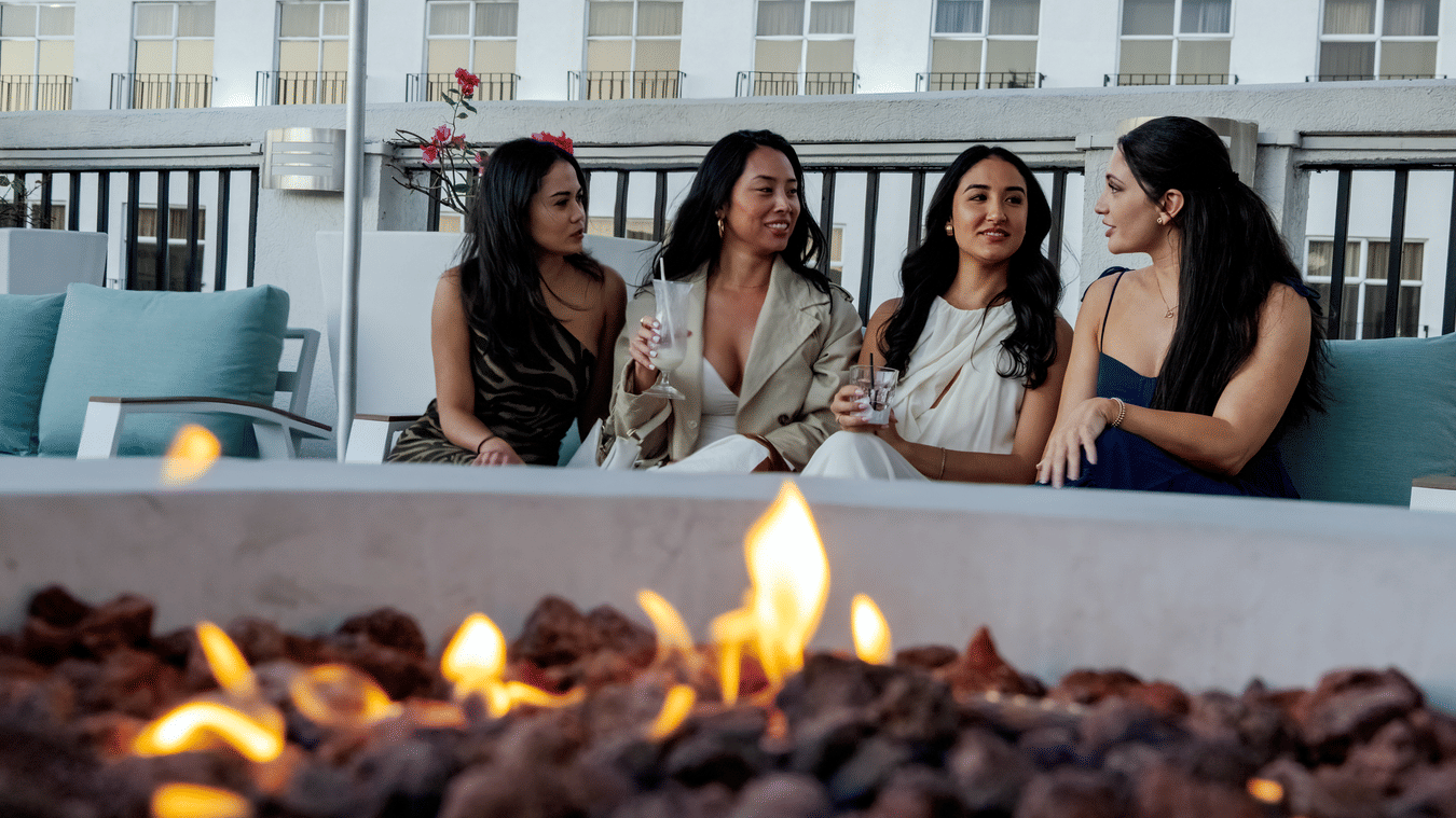 A group of women sitting and chatting near a fire pit at the rooftop lounge at S Hotel Kingston.