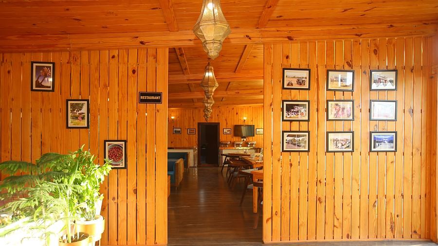 Entryway to the dining area featuring wall-mounted photo frames, a hanging lamp, and potted plants on the side at Aanandam Resort & Spa