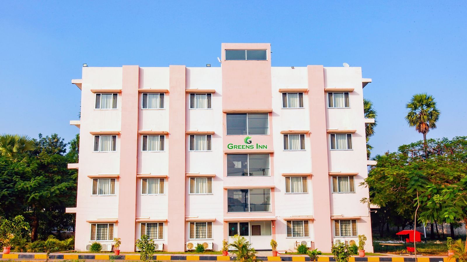 Facade of Greens Inn surrounded by trees during daytime - Tranquil Hotel in Hyderabad.