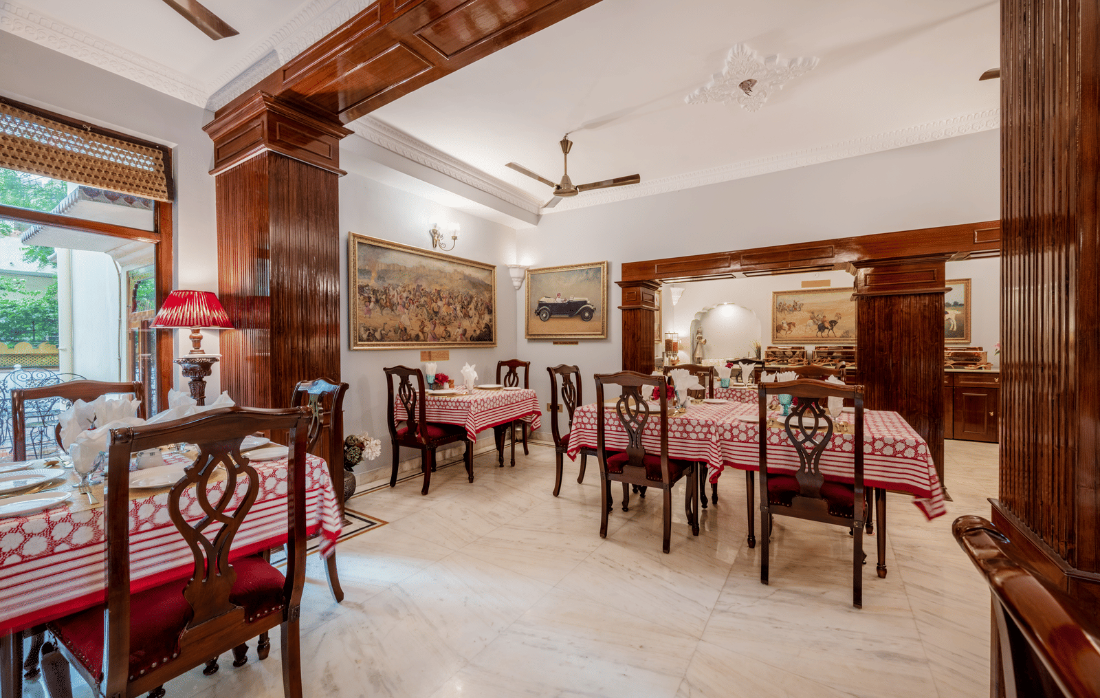 Spacious dining area with wooden chairs, tables, and ceiling fans under exposed beam ceiling at Dera Rawatsar, Jaipur.