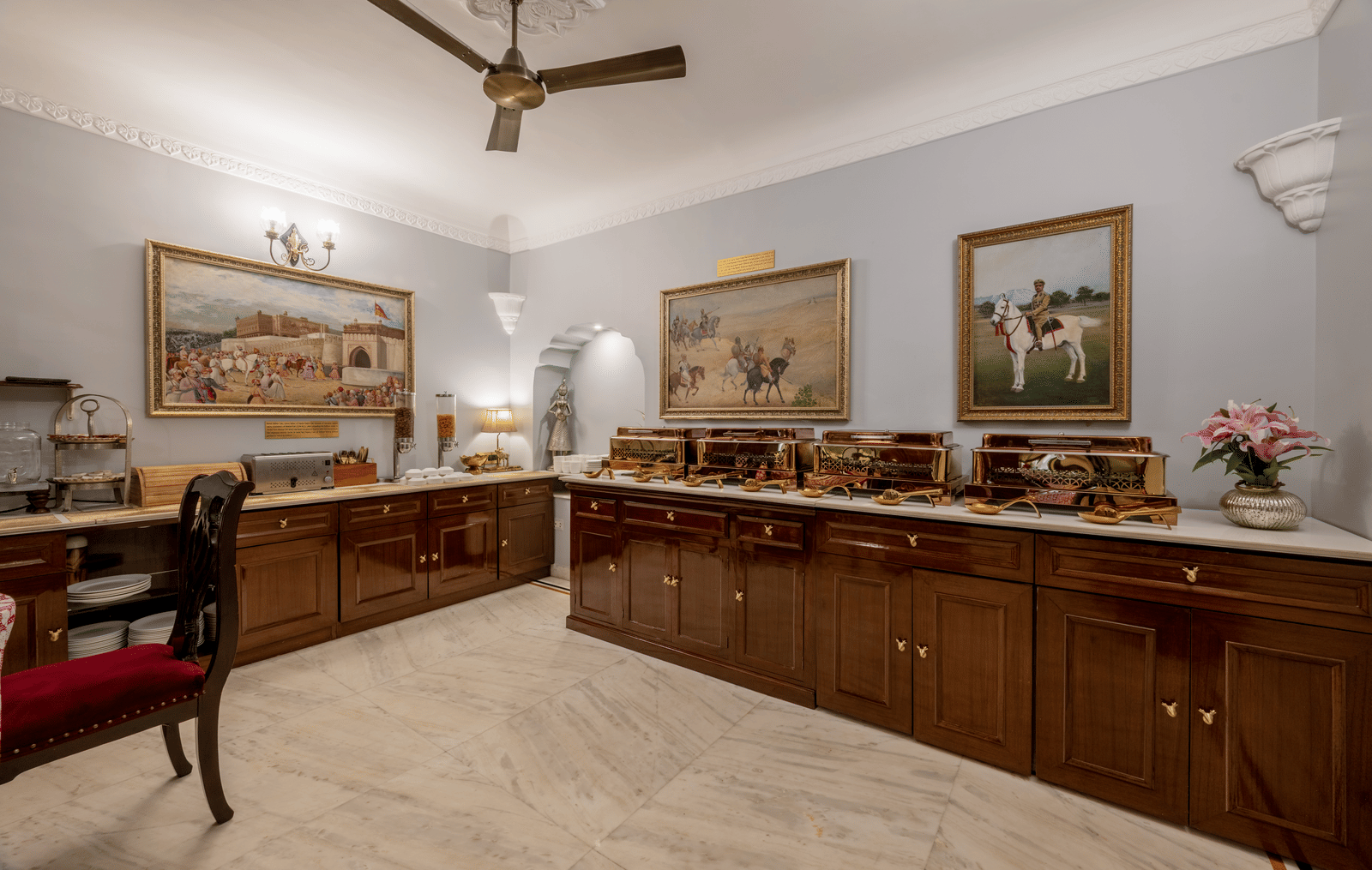 Dining space with wooden desk, framed artwork on walls, and tiled flooring at Dera Rawatsar, Jaipur.