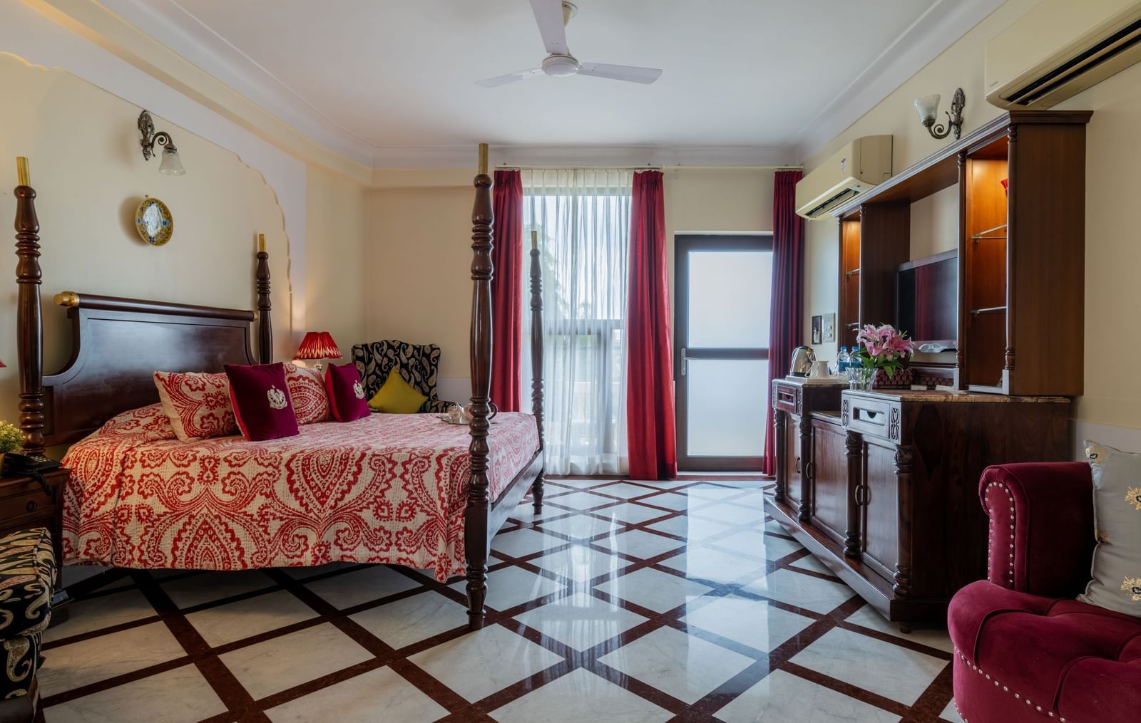  Bedroom with floral bedspread, wooden furniture, and doors opening to balcony at Dera Rawatsar, Jaipur.