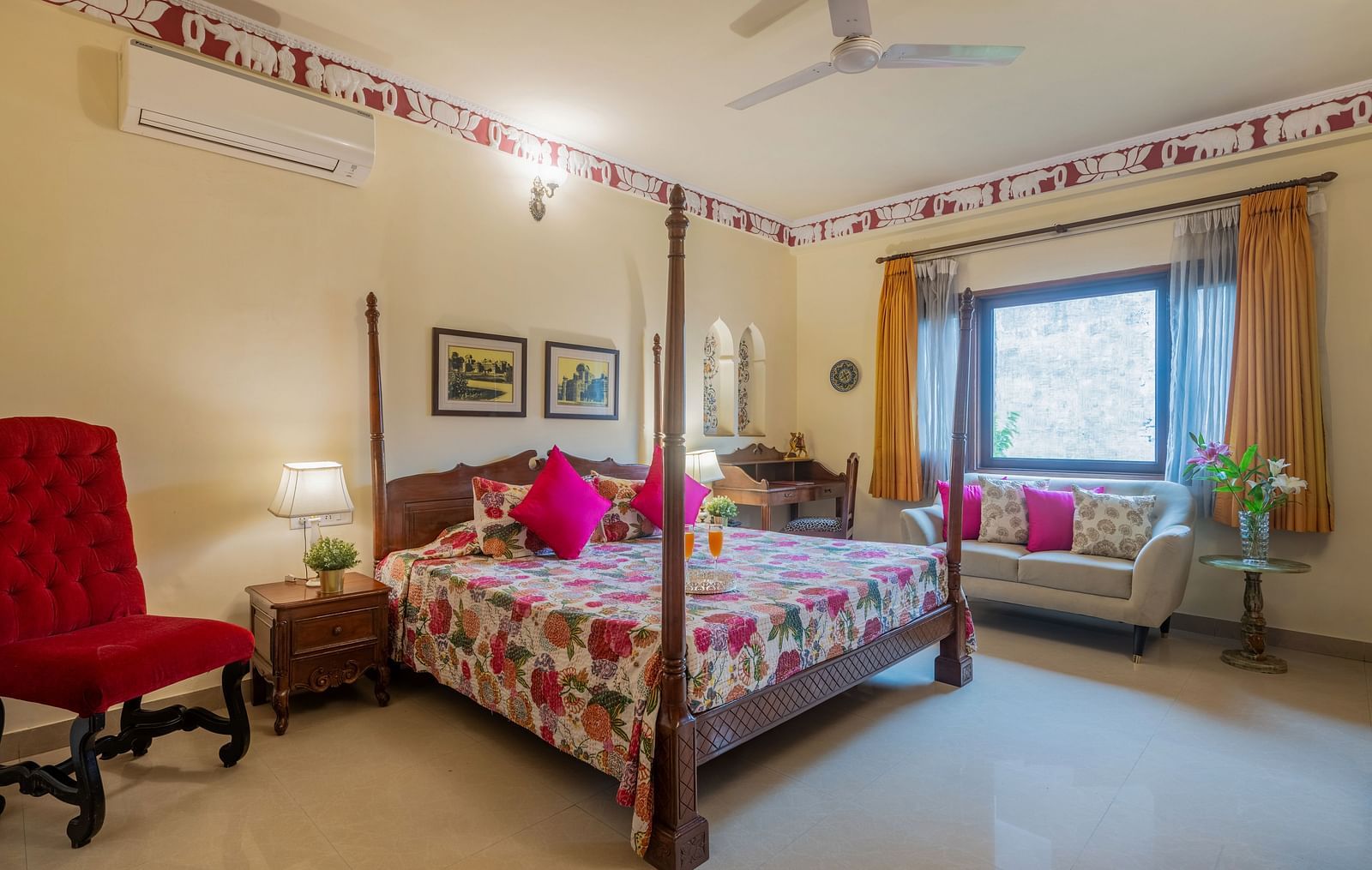 A spacious bedroom at Dera Rawatsar, Jaipur, features a four-poster bed, a comfortable sofa, a stylish armchair, and a dressing table.